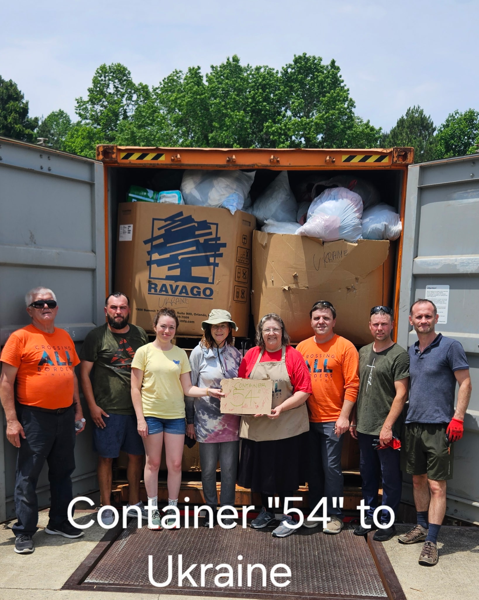 Picture of volunteers standing in front of freshly packed container for Ukraine